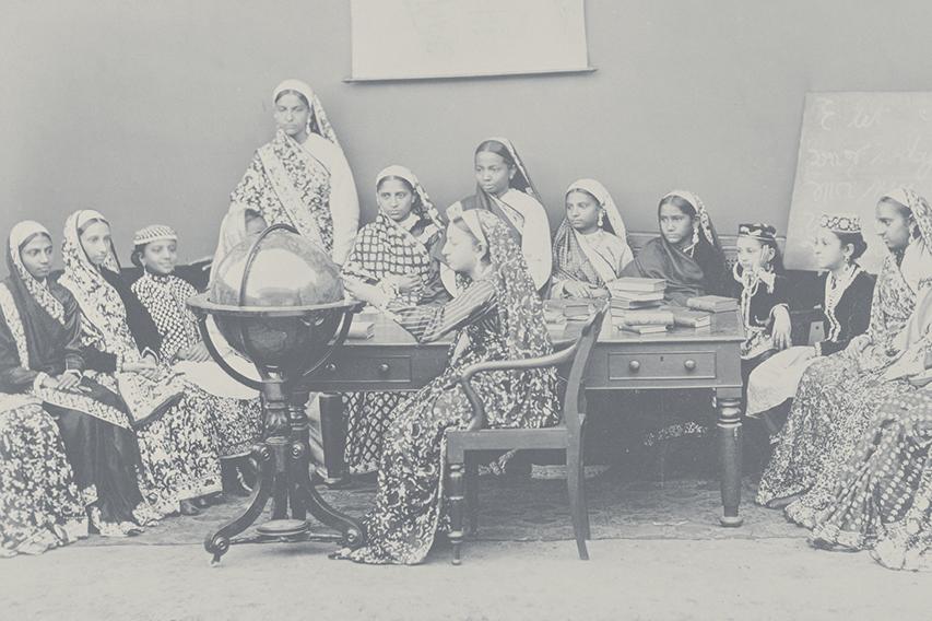 Picture of women in Indian dress looking at a globe in a classroom